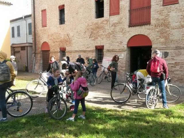 Gruppo di adulti e bambini in bicicletta davanti al Museo