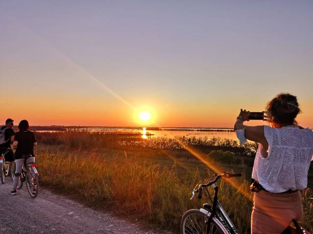 Una ciclista fotografa il tramonto durante la Pedalata dei Fenicotteri